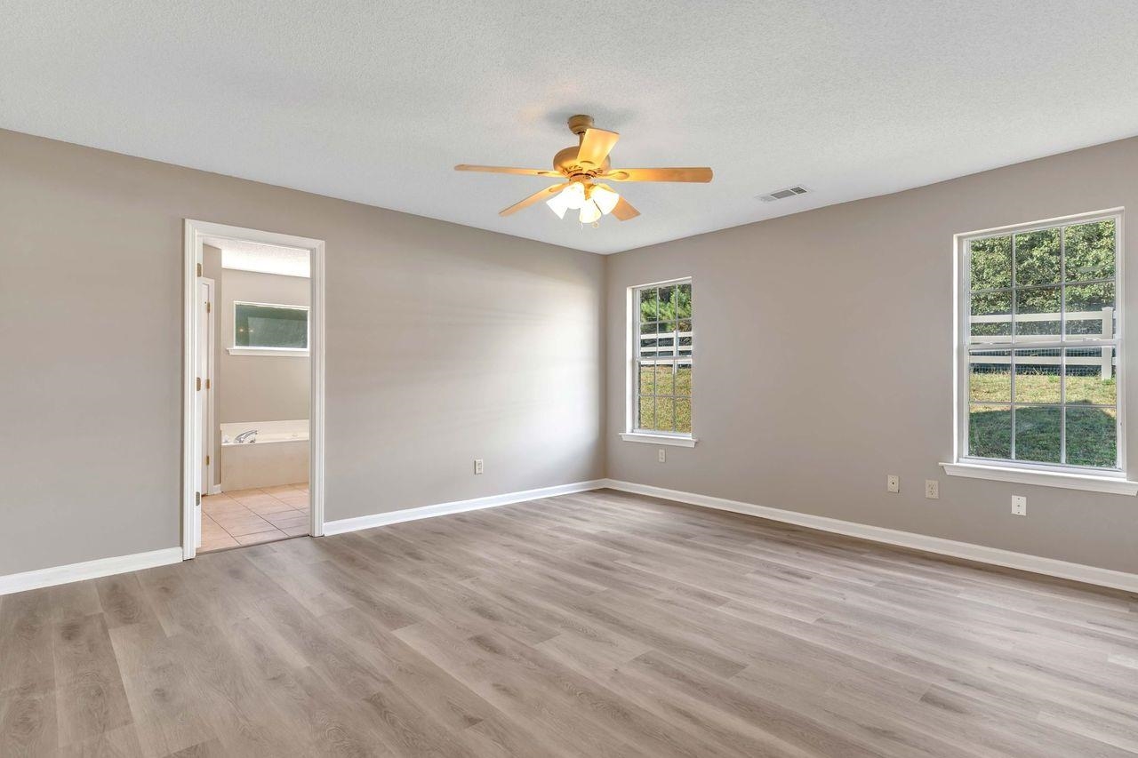 1088 Akins Store Road Munford, TN 38058 - Photo 15 of 40 an empty room with wooden floor chandelier fan and windows