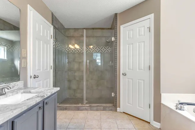 a bathroom with a granite countertop sink a mirror and a shower