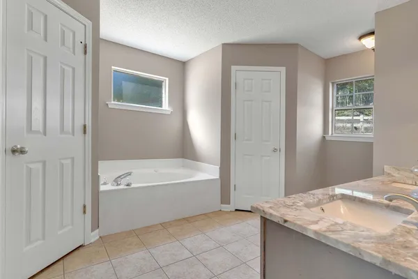 a spacious bathroom with a granite countertop sink a bathtub and window