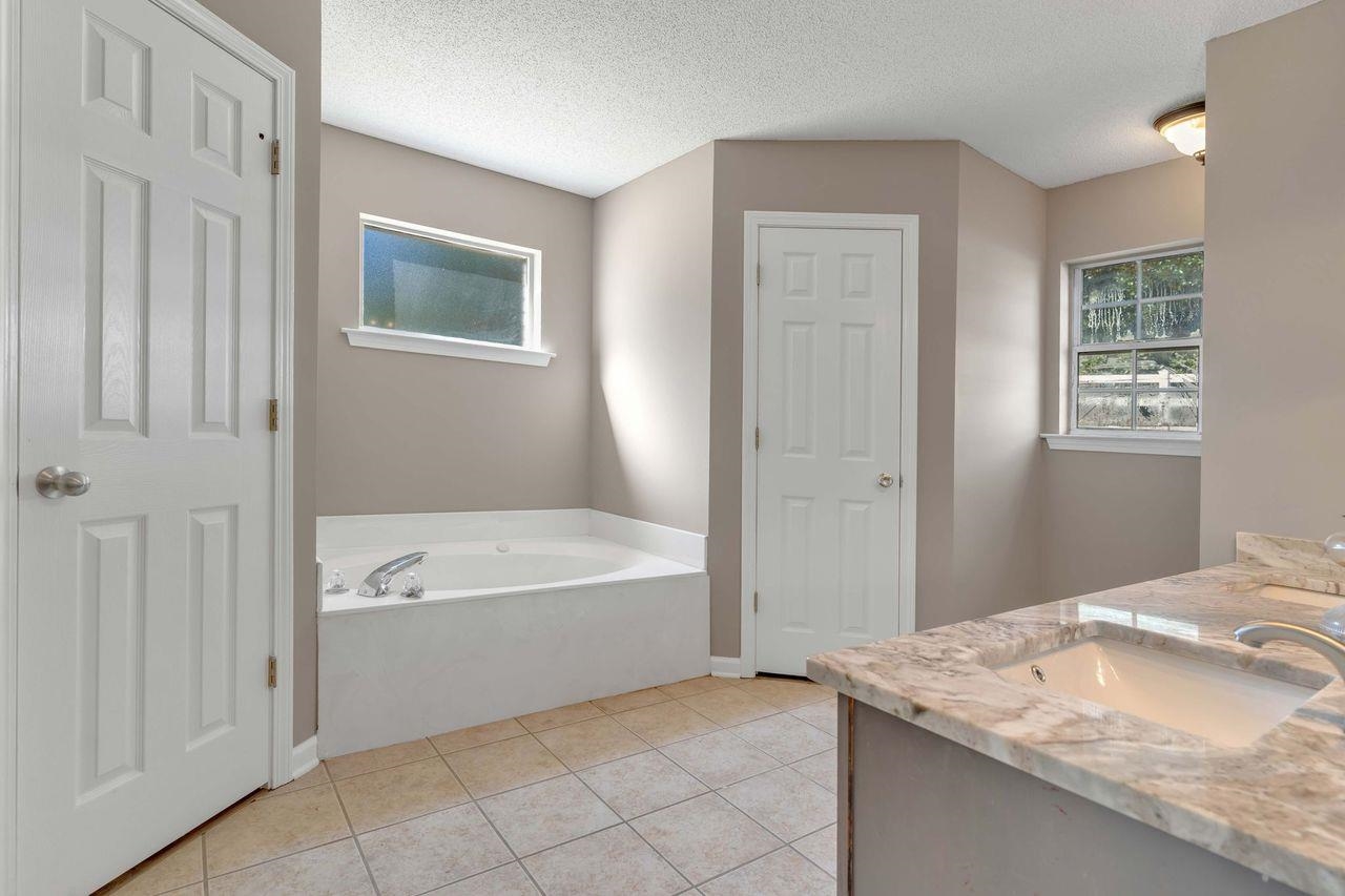 1088 Akins Store Road Munford, TN 38058 - Photo 18 of 40 a spacious bathroom with a granite countertop sink a bathtub and window