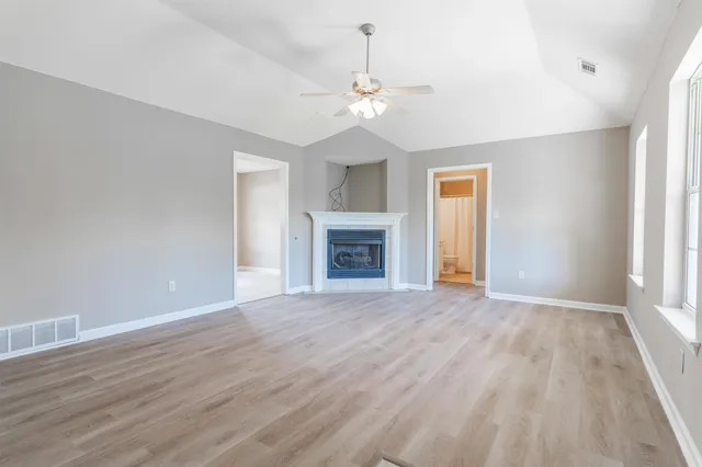 an empty room with wooden floor fireplace and windows