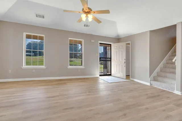 a view of an empty room with window and wooden floor