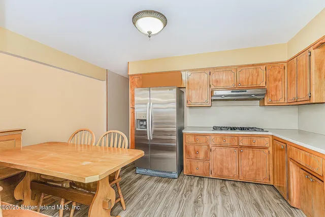 a kitchen with stainless steel appliances granite countertop a sink a stove a dining table and chairs with wooden floor