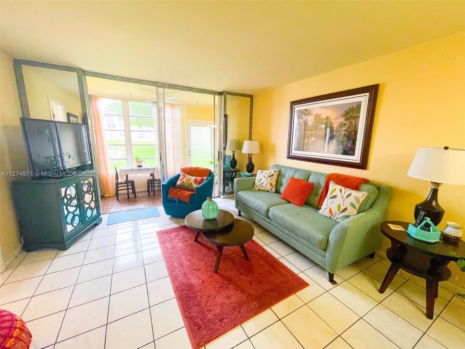 2811 North Pine Island Road, Unit 111 Sunrise, FL 33322 - Photo 11 of 16 a living room with furniture and a floor to ceiling window