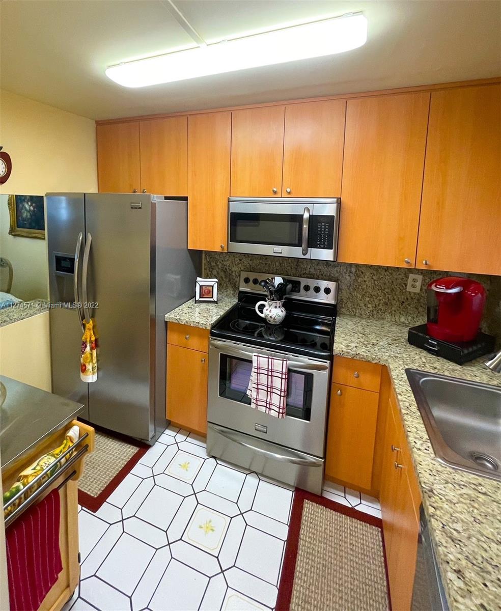 2811 North Pine Island Road, Unit 111 Sunrise, FL 33322 - Photo 4 of 16 a kitchen with stainless steel appliances granite countertop a stove a sink and a microwave