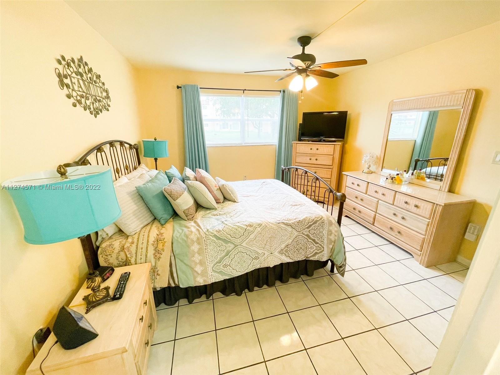 2811 North Pine Island Road, Unit 111 Sunrise, FL 33322 - Photo 6 of 16 a bedroom with a bed and flat screen tv