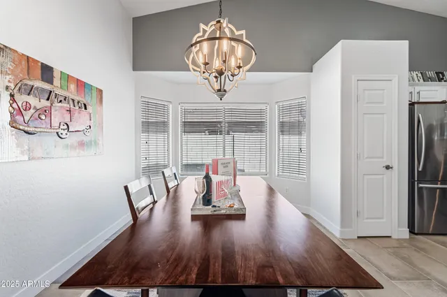 a kitchen with stainless steel appliances kitchen island granite countertop a dining table chairs and a refrigerator