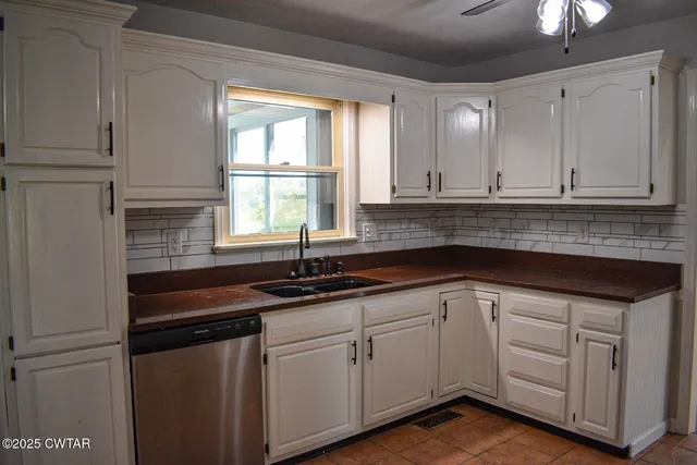 a kitchen with white cabinets and sink
