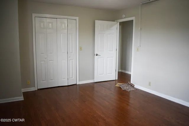 an empty room with wooden floor and closet area