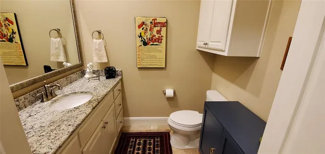 a bathroom with a granite countertop toilet sink and mirror