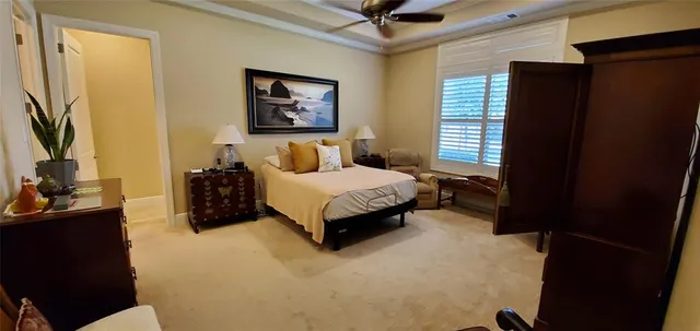 a spacious bedroom with a bed painting on wall and a large window