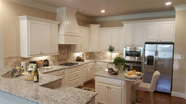 a kitchen with stainless steel appliances granite countertop a sink stove refrigerator and cabinets