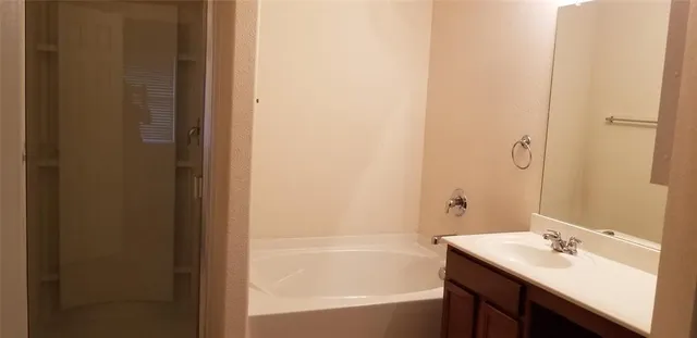 a bathroom with a tub sink vanity and a mirror