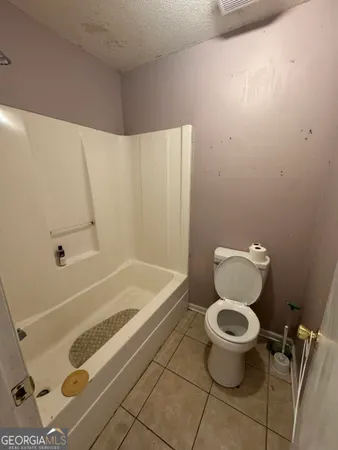 a bathroom with a granite countertop toilet and a bathtub