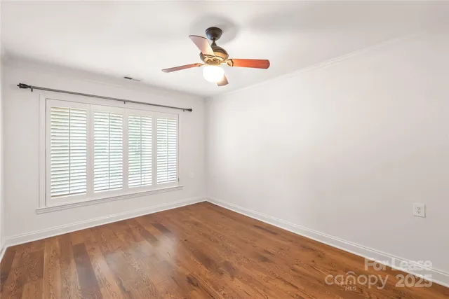 an empty room with wooden floor fan and windows