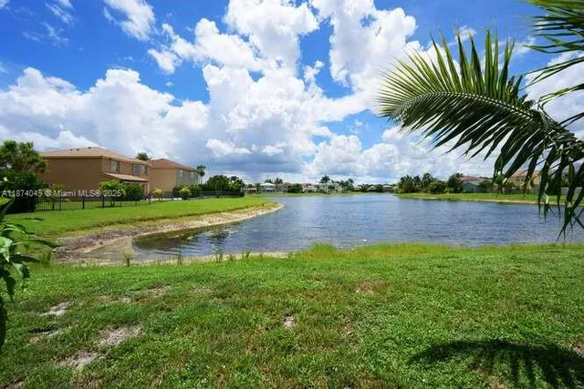 a view of a lake with a big yard and palm trees