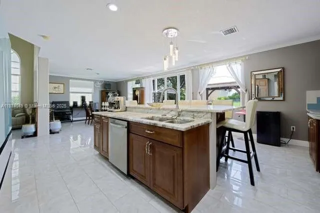 a kitchen with kitchen island granite countertop a sink and a refrigerator