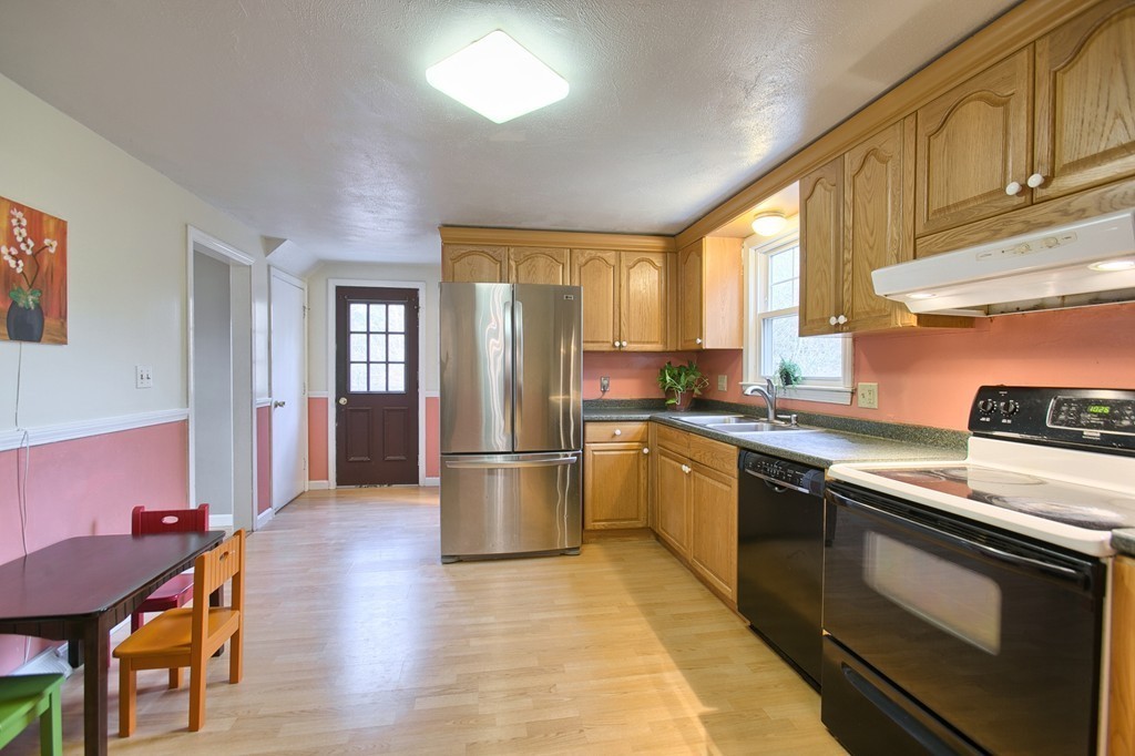 116 Crooked Spring Road Chelmsford, MA 01863 - Photo 7 of 24 a kitchen with stainless steel appliances granite countertop a refrigerator a stove a sink dishwasher with a dining table and chair