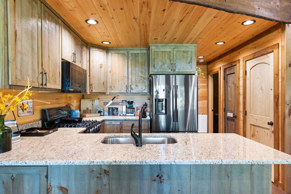 89 Whispering Hawk Trail Morganton, GA 30560 - Photo 9 of 33 a kitchen with stainless steel appliances granite countertop a refrigerator a stove and a sink with wooden cabinets