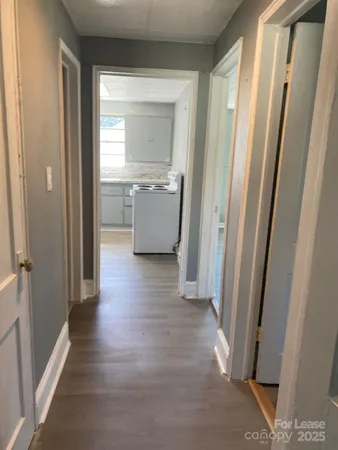a view of a hallway with wooden floor and a kitchen