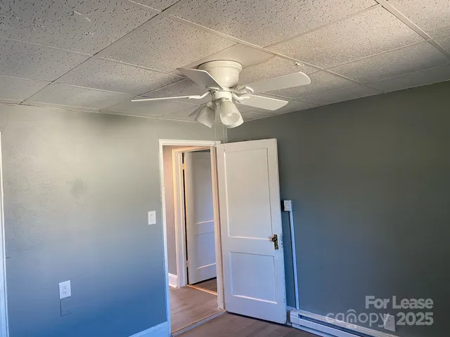 an empty room with wooden floor and a ceiling fan