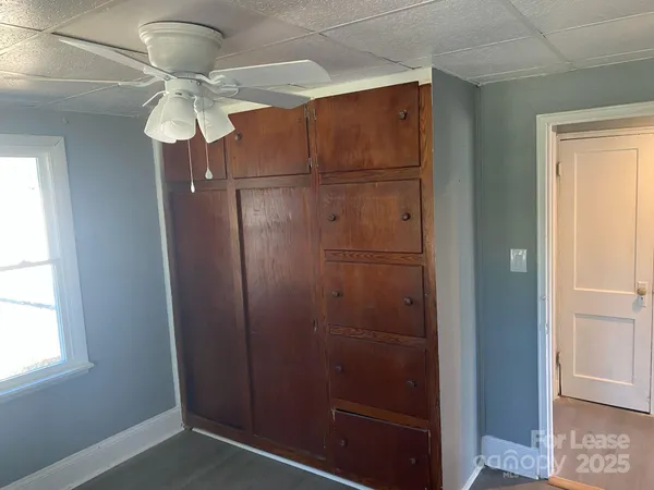 an empty room with wooden floor fan and windows
