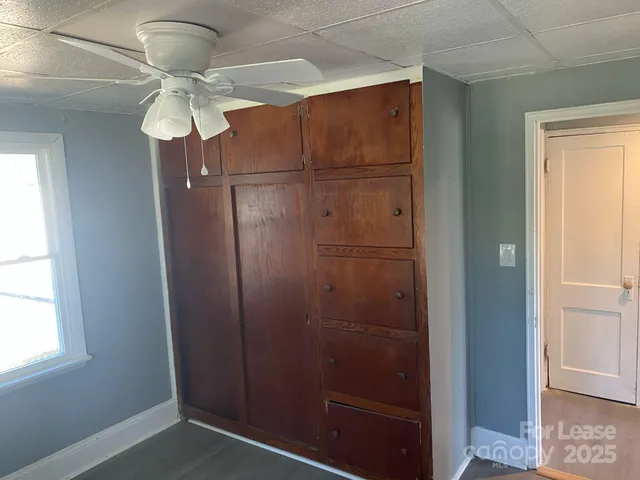 an empty room with wooden floor fan and windows
