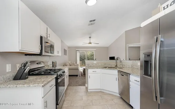 a kitchen with stainless steel appliances granite countertop a sink stove refrigerator and cabinets