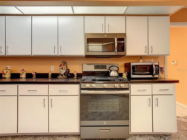 a kitchen with stainless steel appliances granite countertop white cabinets and a stove top oven