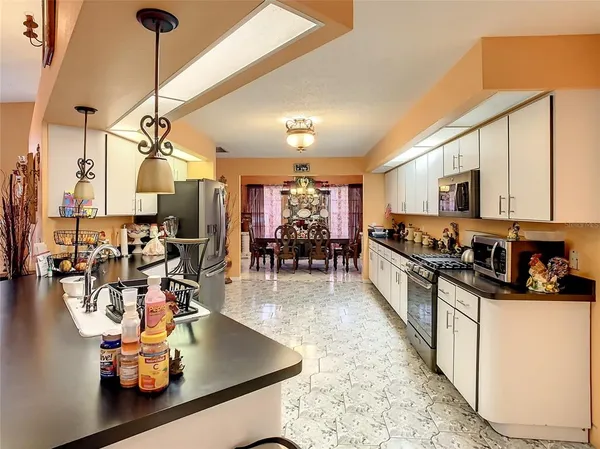 a kitchen with stainless steel appliances granite countertop a sink counter space and living room view