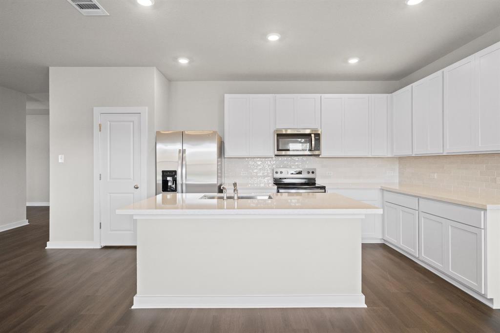 177 Sleep Hollow Jarrell, TX 76537 - Photo 6 of 24 Modern kitchen featuring a central island, light countertops, white cabinetry, and stainless steel appliances