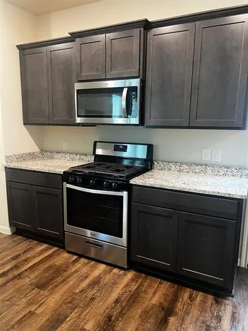 a kitchen with granite countertop a stove and a microwave