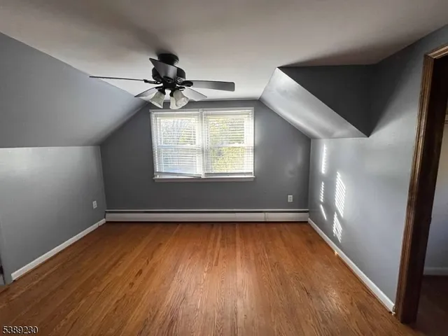 an empty room with wooden floor chandelier fan and windows