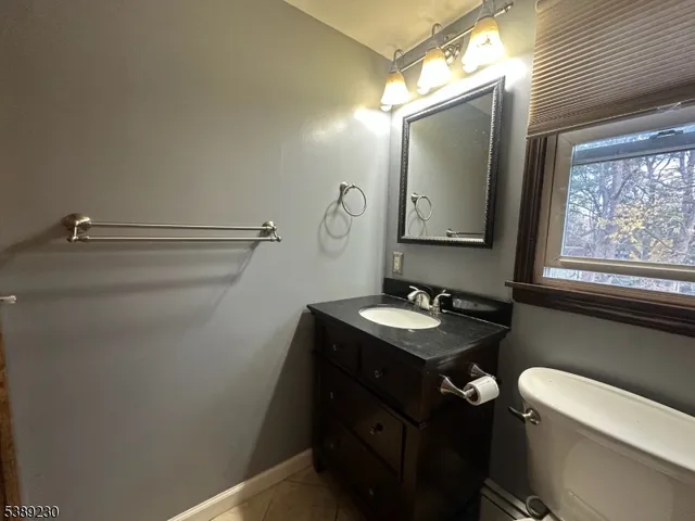 a bathroom with a granite countertop sink mirror vanity and toilet