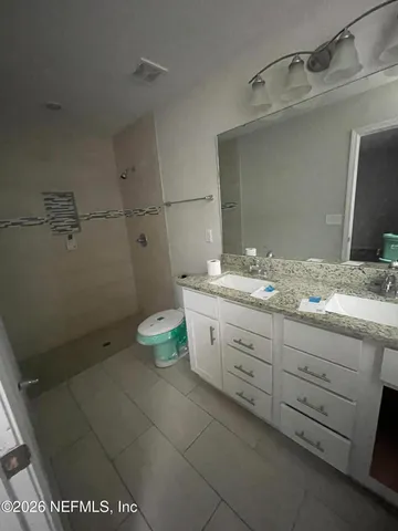a bathroom with a granite countertop sink a toilet and a mirror
