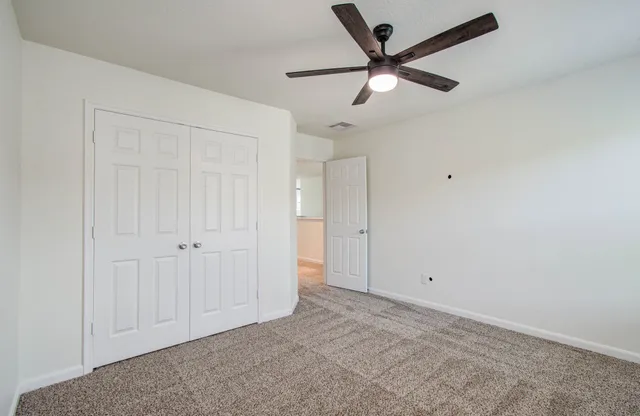an empty room with closet and a chandelier fan