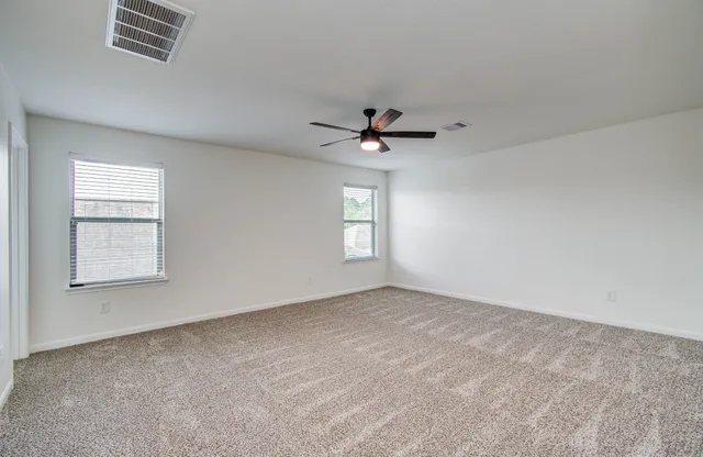 an empty room with windows and fan