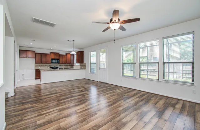 a view of an empty room with kitchen and window