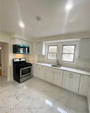 a large kitchen with kitchen island granite countertop a sink and a stove top oven