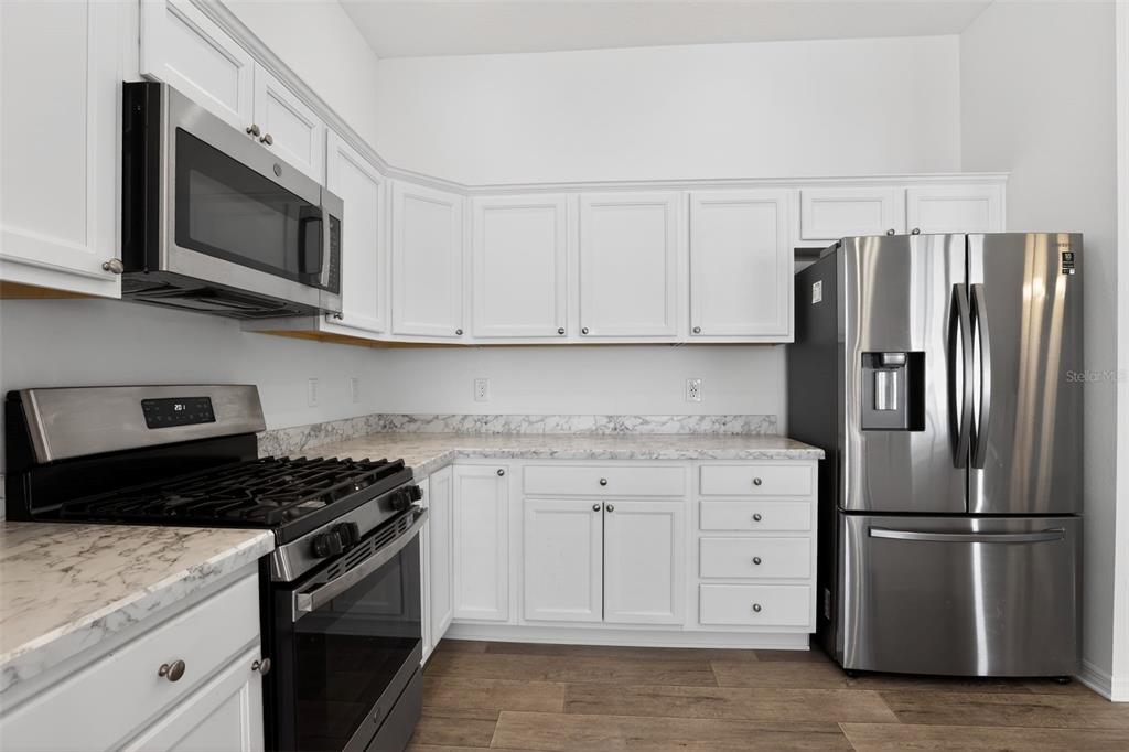 6273 Windham Way The Villages, FL 32163 - Photo 11 of 32 a kitchen with stainless steel appliances granite countertop a refrigerator stove a sink and dishwasher with white cabinets