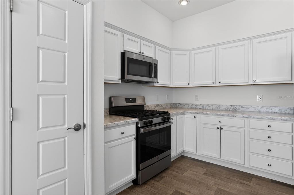 6273 Windham Way The Villages, FL 32163 - Photo 13 of 32 a kitchen with white cabinets and stainless steel appliances