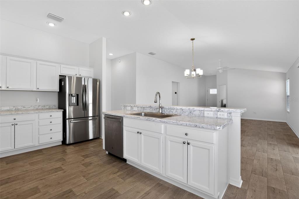 6273 Windham Way The Villages, FL 32163 - Photo 14 of 32 a kitchen with a sink dishwasher a white stove refrigerator and cabinets with wooden floor