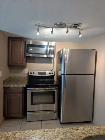 a kitchen with granite countertop a refrigerator and a stove