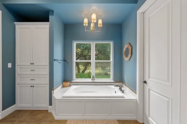 a bathroom with a tub a window and a chandelier