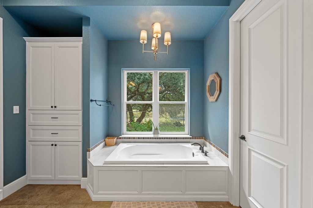 151 Kerr Canyon Pass South Kerrville, TX 78028 - Photo 13 of 45 a bathroom with a tub a window and a chandelier