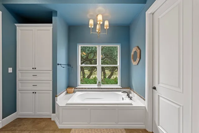 a bathroom with a tub a window and a chandelier