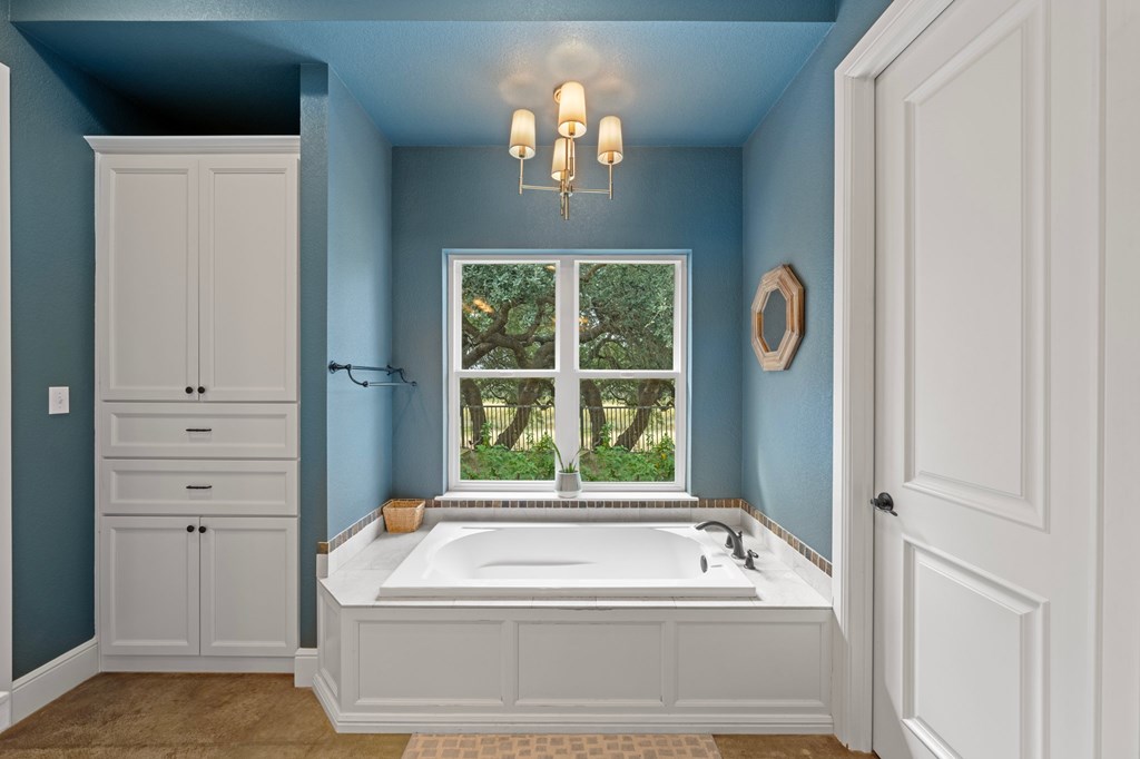 151 Kerr Canyon Pass South Kerrville, TX 78028 - Photo 14 of 45 a bathroom with a tub a window and a chandelier