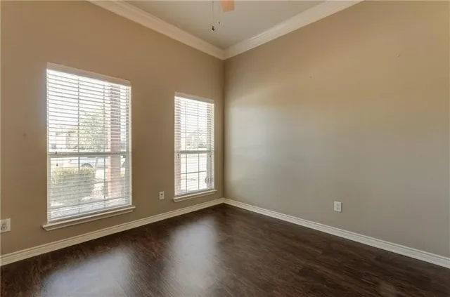 an empty room with wooden floor and windows with curtains