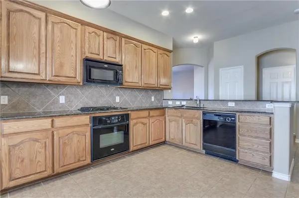 a kitchen with granite countertop white cabinets and stainless steel appliances