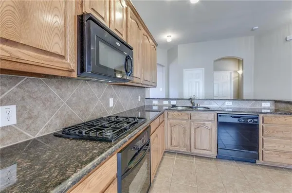 a kitchen with stainless steel appliances granite countertop a stove a sink and a microwave